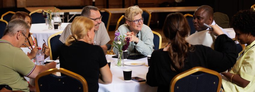 Image of people sitting around a table laughing and discussing