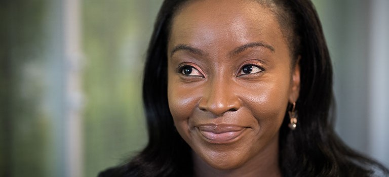 Yetunde looking upwards with a smile wearing earrings and long dark hair